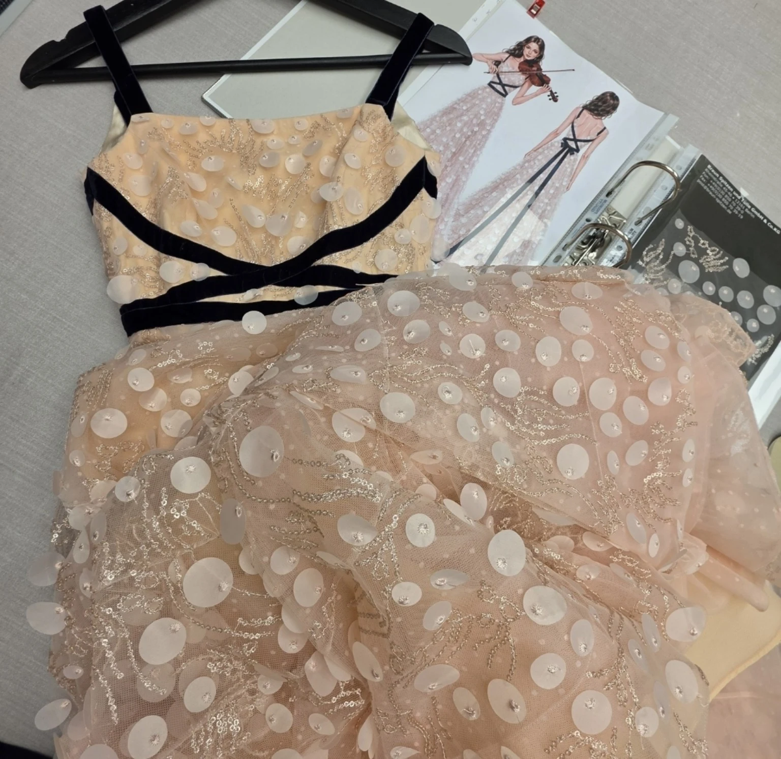 Couture gown with fabric appliqués and dark velvet ribbon, alongside its design sketch